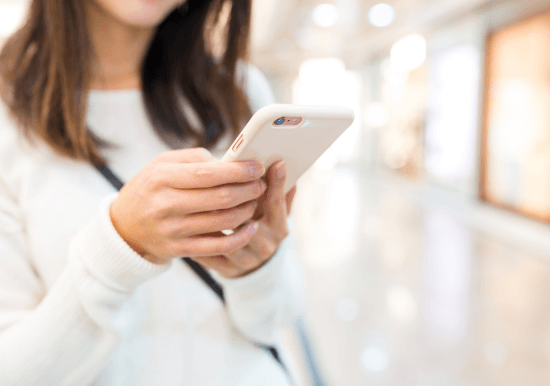 Image of a woman standing in a store looking at her phone