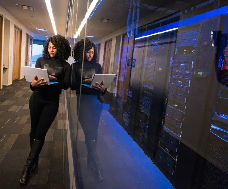 Image of a woman leaning against a wall using her laptop