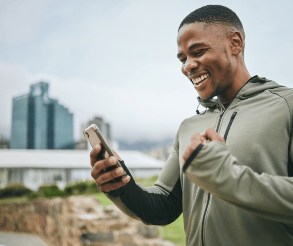 A woman walking down the street with headphones laughing at her phone